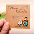 Detail of daisy and butterfly enamel charms with lobster clasp on a kraft card - Blue