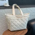 Chic cream quilted tote bag with diamond stitching and side pockets on wooden table - White