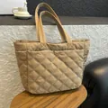 Gesteppte beige Tragetasche mit Rautenmuster und großem Fassungsvermögen auf Holztisch - Khaki