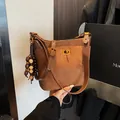 Vintage bruine bucket bag van mat suède met goudkleurige draaisluiting en kwastje - Met Hanger / Bruin