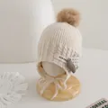 Dettaglio cappello in maglia per neonati con pompon marrone, paraorecchie e lacci in posa - 3-10 anni / Beige