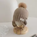 Dettaglio della maglia e del ciondolo a cuore su un cappello beige per bimbi - 3-10 anni / Marrone