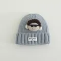 Dettaglio del berretto in maglia azzurro con bambola dei cartoni e capelli ricci - Taglia unica (3-10 anni) / Blu grigio