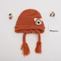 Detail of ginger orange knit baby hat featuring cute bear patch and braided tassels - Baby One Size Elastic / Bear Orange Coffee