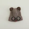 Detailed knit texture of a brown children's bear hat with cartoon glasses and 3D ears - Brown