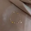 Dettaglio dei ciondoli stella e luna con perle su un bracciale in oro rosa raffinato - Bracciale Perla Zircone Stella Luna Giallo