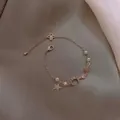 Bracciale in oro rosa con ciondoli stella e luna, perle e cristallo rosa, vista dall'alto - Bracciale Perla Zircone Stella Luna Rosa