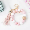 Detail of pink silicone beads, wooden accent, and leather tassel on a gold keychain ring - Pink Heart Print