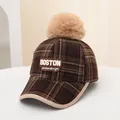 Detail view of winter plaid baseball cap with BOSTON embroidery and large faux fur pompom - Kids (48-54CM) / BOSTON Coffee Plaid