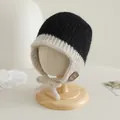 Dettaglio del cappello in maglia per neonati con paraorecchie, patch smiley e lacci crema - Nero