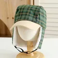 Detail of winter trapper hat showing green plaid fabric and warm white faux shearling lining - Kids / Green
