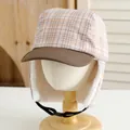 Detail of warm winter trapper hat with plaid pattern and soft white faux fur lining - Kids / Coffee