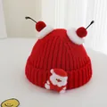 Detail of red knit Christmas hat with soft pompoms and a cute Santa Claus patch - One Size / Red