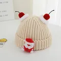 Detail of chunky knit beige Christmas hat for kids with Santa doll and red cherry pom-poms - One Size / Beige