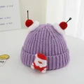 Detail view of purple knitted Christmas hat with Santa applique and red pompoms - One Size / Purple