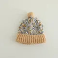 Dettaglio macro della trama in maglia colorata a fiocco di neve e pompon morbido - 2-5 Anni / Caffè Chiaro