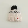 Detailed view of knitted winter hat featuring a fluffy pom pom and lace patch detail - Kids 3-8 Years (Elastic) / Black Ball