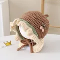 Detailed close-up of knitted baby bonnet with avocado green trim and cherry patch - Toddlers 1-3 Years / Coffee