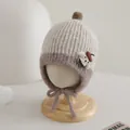 Detail of knit baby hat with earflaps, pom-pom and bear patch in beige and brown - Toddler Size / Off White And Light Coffee