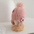 Détail du bonnet tricoté rose pour bébé avec pompons et applique florale délicate - Style Élastique pour Enfants / Rose