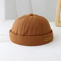 Dettaglio del cappello Miki caramello con targhetta in metallo KUKUJI e tessuto - 50-52cm / Caffè