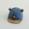 Close-up of the plush bear ears and stitched patch on a blue baby baseball cap - Toddler One Size / Blue