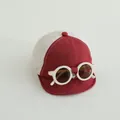 Dettaglio del cappellino neonato in rete con occhiali decorativi e visiera rossa - Borgogna