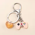 Dettaglio del ciondolo controller in resina e cuore arancione su un portachiavi in metallo - Rosa Arancio
