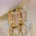 Macro shot of U-shaped gold earrings featuring micro-paved pink zircon stones - Gold Color With Pink Stones