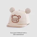 Detail van een crème babypetje met 3D-beertjesoren en bruin geborduurde letters - 45-48 cm / Beige