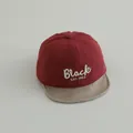 Close-up of baby baseball cap with red fabric and beige woven brim featuring Black embroidery - 45-48cm (0-3 Years) / Burgundy