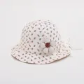 Close-up of floral baby sun hat fabric featuring 3D fabric flower and brand label detail - Toddler Size / Pink Floral on Cream
