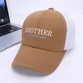 Detail of a brown mesh trucker hat with BROTHER ON THE ROAD embroidery next to a laptop - Kids 2-8 Years (50-53CM) / Dark Coffee