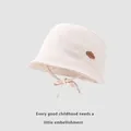 Detail of baby sun hat featuring soft cream cotton fabric and brown cloud patch detail - Beige / 48-52cm