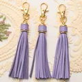 Three light purple PU leather tassels with gold lobster clasps on white lace fabric - Purple