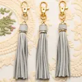 Three light gray PU leather tassels with polished golden lobster clasps on lace - Gray