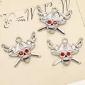 Macro shot of silver pirate skull charms with red rhinestone eyes on vintage paper - Silver Red Eye Pirate Skull Style