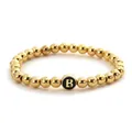 Dettaglio del bracciale elastico con perline dorate e ciondolo nero con lettera B - Stile Lettera B