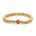 Detail of a beaded gold bracelet with a red enamel circular charm featuring the letter N - Letter N Style