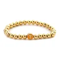 Detailed macro view of gold alloy beaded elastic bracelet with letter T charm - Letter T Style