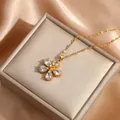 Elegant gold flower pendant necklace with pear-shaped cubic zirconia on satin background - White