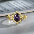 Elegant gold ring with oval purple crystal and sparkling side zircons on a magazine - US 6 / Purple