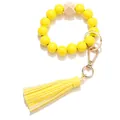 Close-up of yellow wooden beads bracelet keychain with leather tassel and gold ring - Yellow