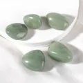Close-up of polished green aventurine stones with natural texture on white silk base - Green Aventurine Raw Stone