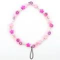 Detailed macro view of colorful beads, pink stars and smiley faces on a phone wrist strap - Pink