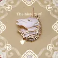 Close-up of golden unicorn brooch with white enamel, colorful rhinestones and crystal eye - White