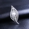 Broche de hoja calada plateada con perla blanca y brillantes sobre fondo de cuero negro - Plateado