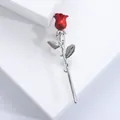 Elegant red rose brooch with silver stem and two leaves on white geometric display - Red