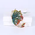 Macro-opname van vlinderbroche met kleurrijke strass steentjes en grote witte parel - Groen