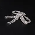 Dettaglio ravvicinato di una spilla a fiocco argentata con strass brillanti - Argento